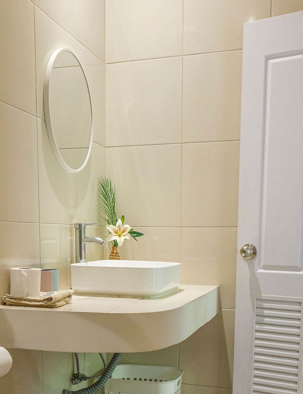 Modern Bungalow 3 — beige tiled bathroom with a vessel basin, round mirror and folded towels