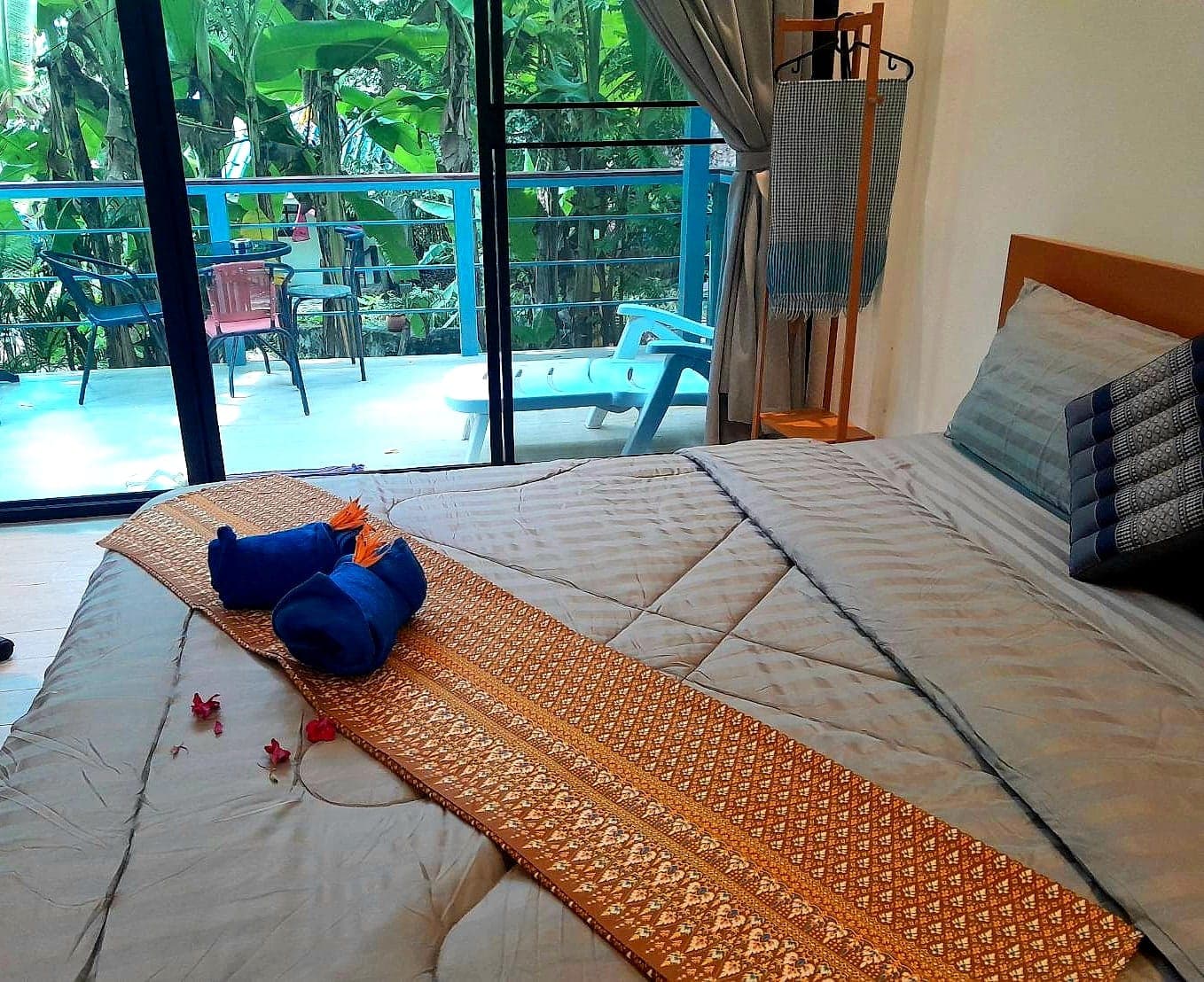 From the bed out to the balcony: table, chairs and a lounger on the deck among banana trees