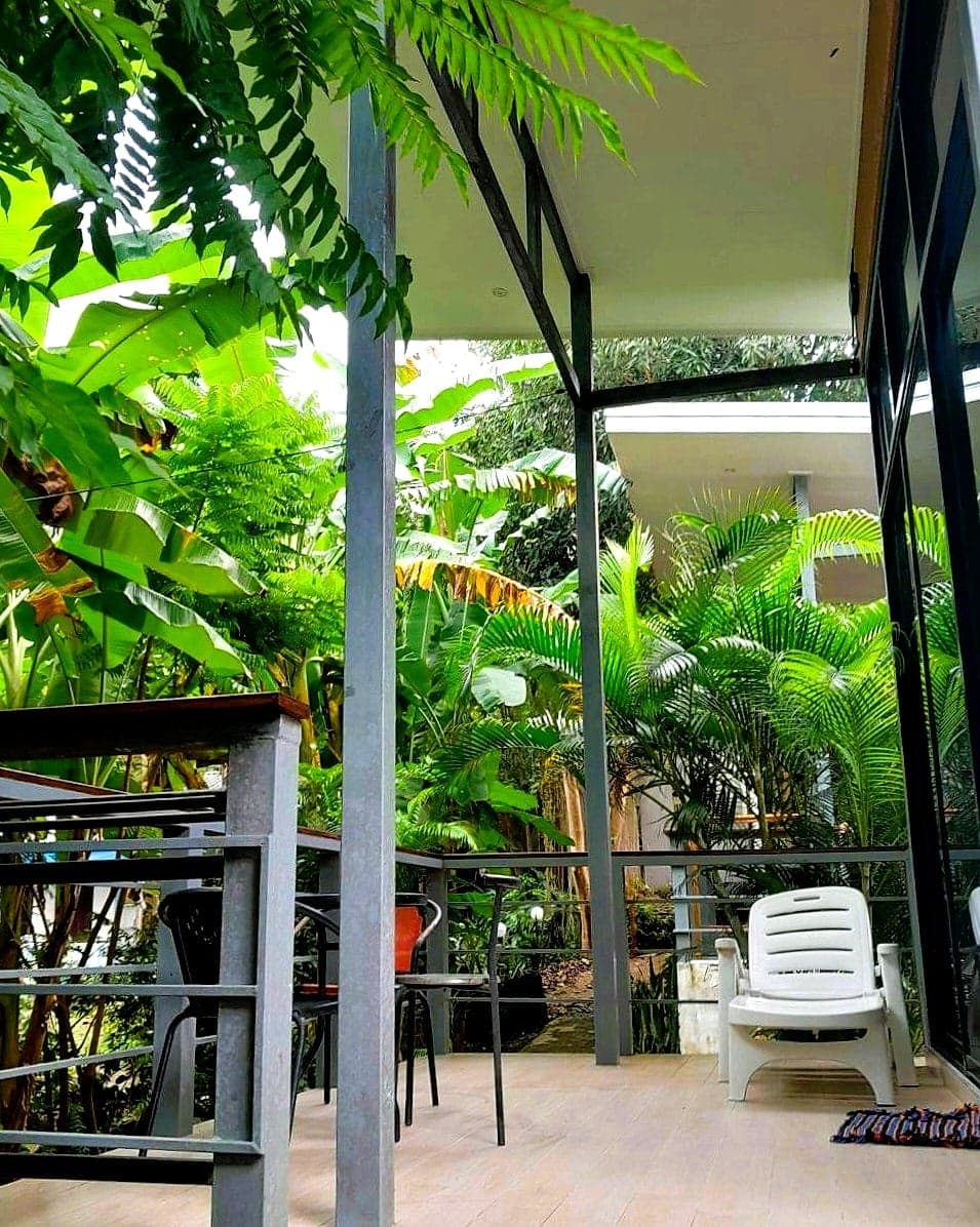 The covered terrace: chairs and a lounger under the roof, looking straight into the greenery